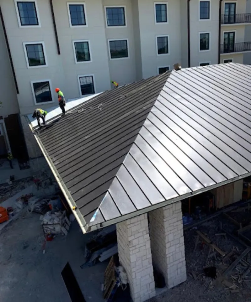 Crew installing standing seam metal roof panels on a commercial project in Dover